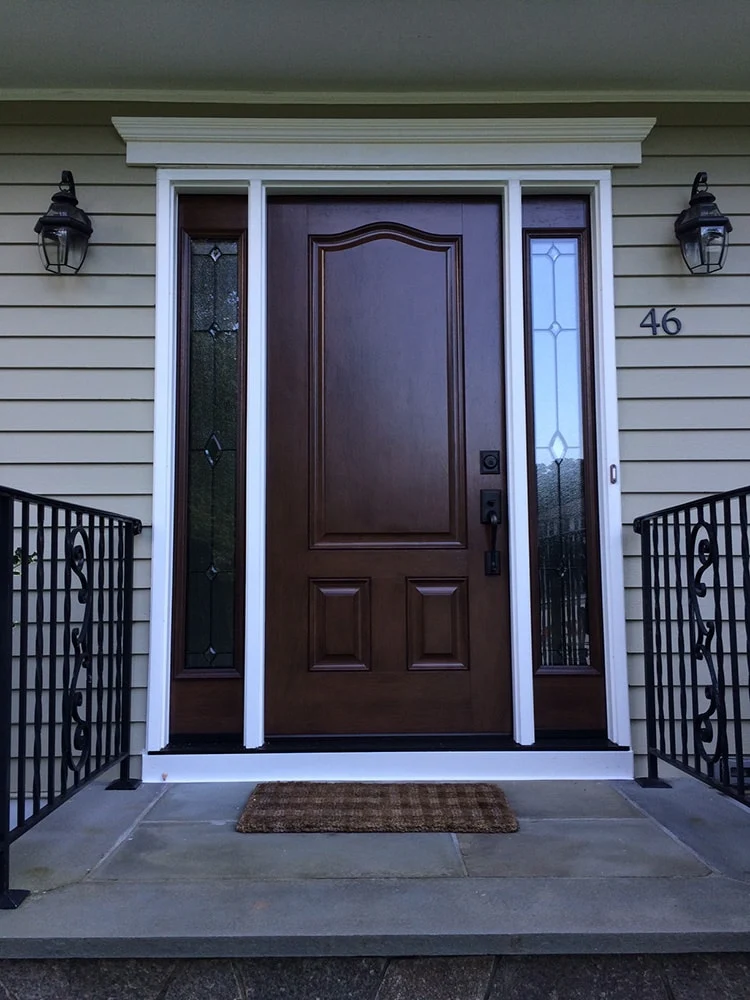 large dark wood entry door with glass side panels