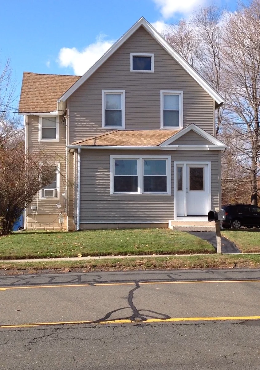 tan vinyl siding, white replacement windows, and gutters installed